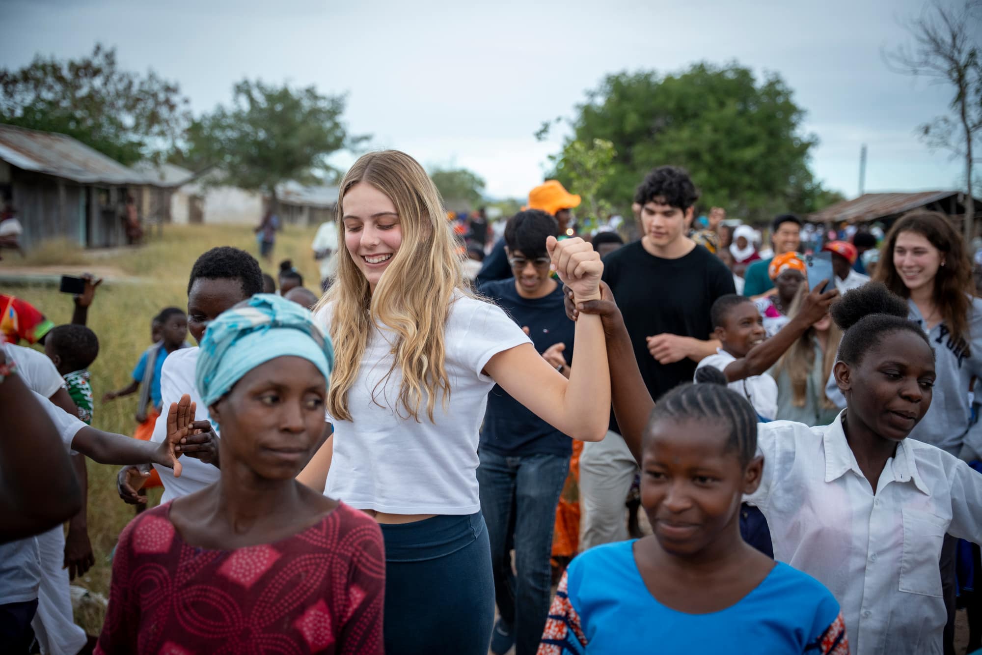 UT GivePower trekkers dancing hand-in-hand with community members during a welcome celebration in Kenya