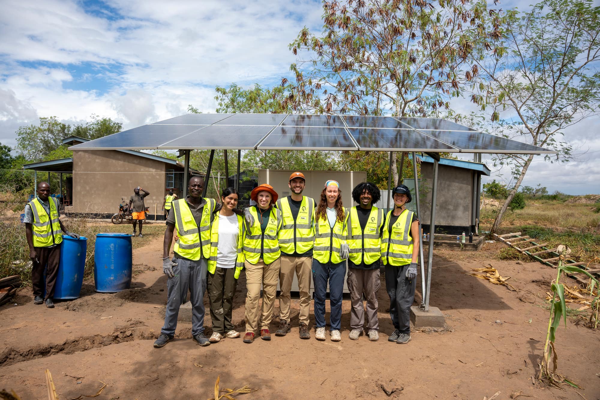 A UT GivePower trek team with local partners under a newly completed solar array in Kenya